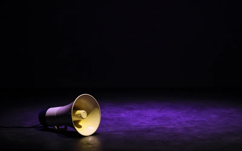 A megaphone on a dark floor under yellow and purple light