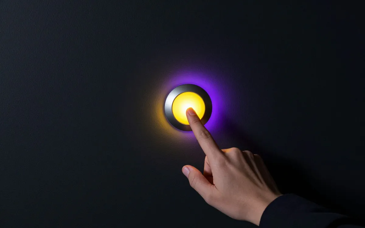 Finger about to press a doorbell on a dark wall