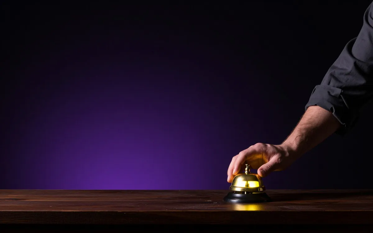 Shop counter bell and a reaching hand under warm light
