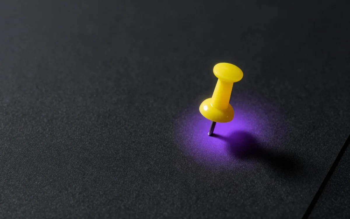 A brass drawing pin on black card, macro