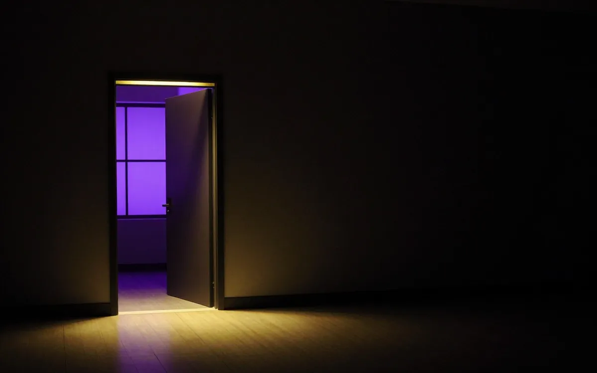 Open doorway spilling warm light down a dark corridor